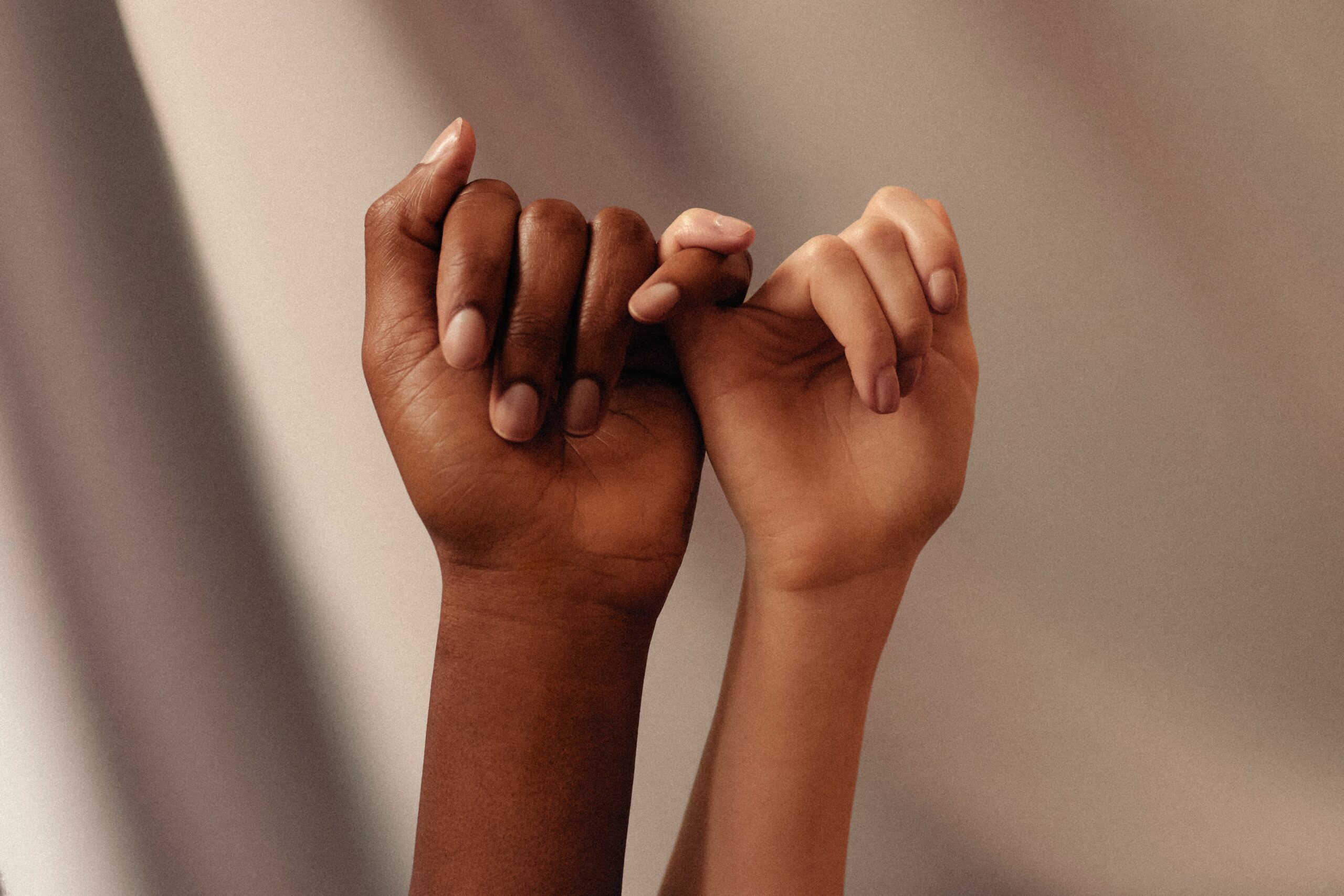 Two hands linked by their pinky fingers
